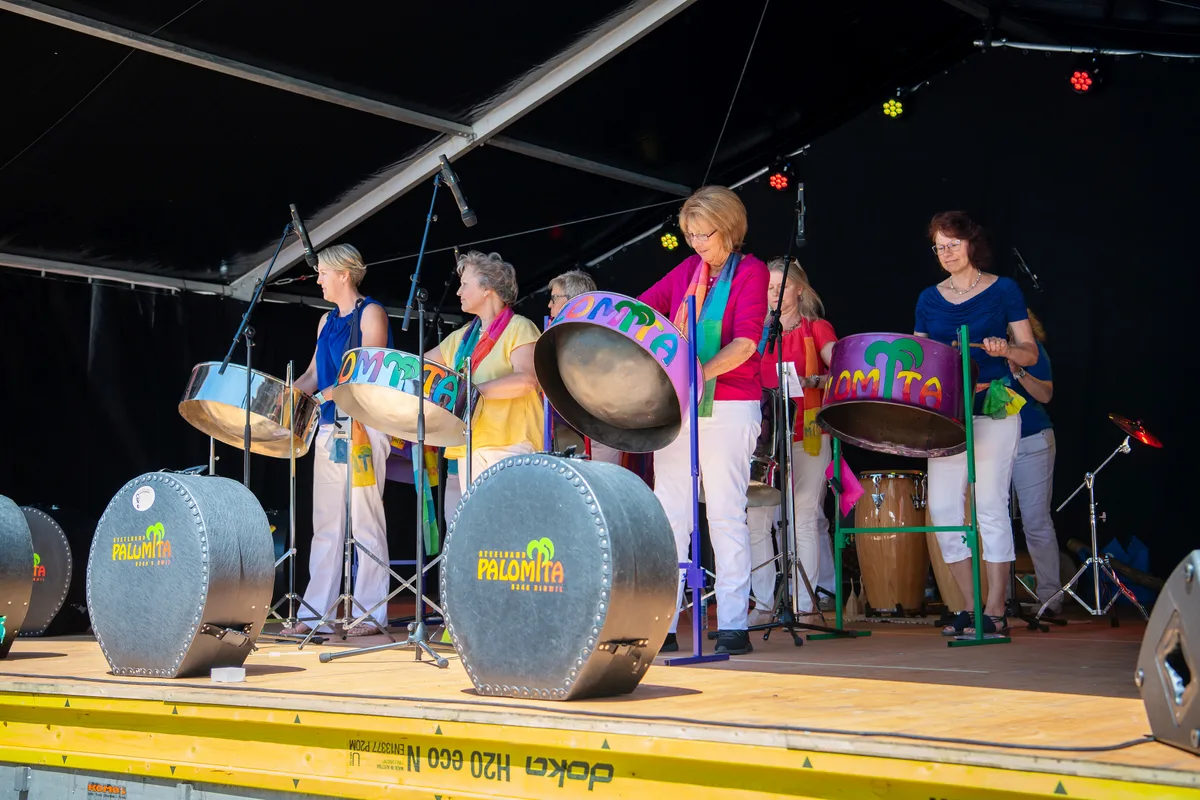 Frauen stehen auf der Bühne und spielen Steeldrums.